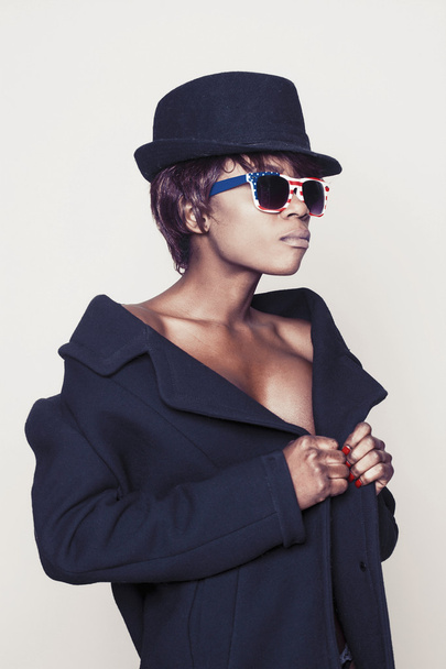 schönes afrikanisches Model mit Mantel, Hut und amerikanischer Sonnenbrille - Foto, Bild