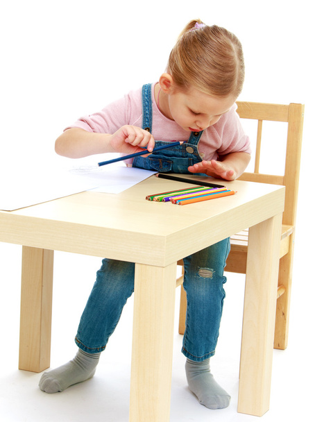 Little girl draws pencils sitting at the table. - Fotó, kép