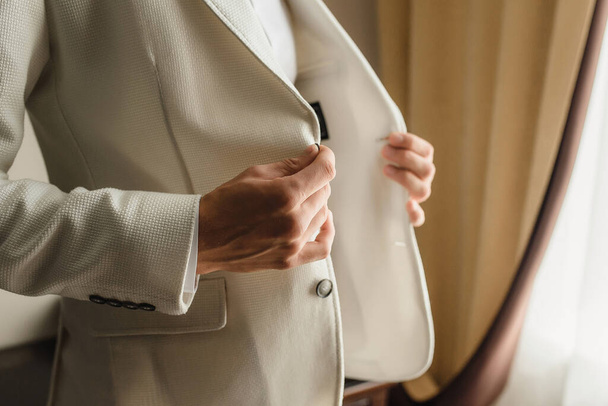 a man puts on a white jacket, fastens a button, business, success. High quality photo - Foto, Bild
