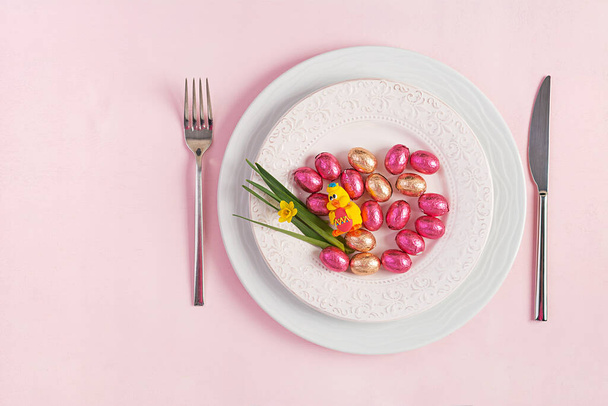 Happy Easter. Table setting for Easter holiday. Easter eggs, duck, flower and cutlery on pink background. Top view, flat lay - Fotoğraf, Görsel