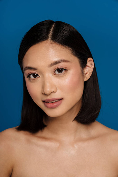 Asian half-naked woman smiling and looking at camera isolated over blue background - Photo, image