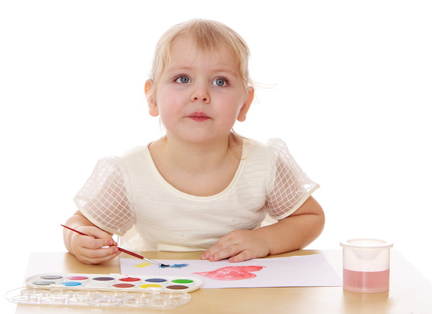 Крупним планом розумна дівчинка малює фарбу, що сидить за столом
. - Фото, зображення