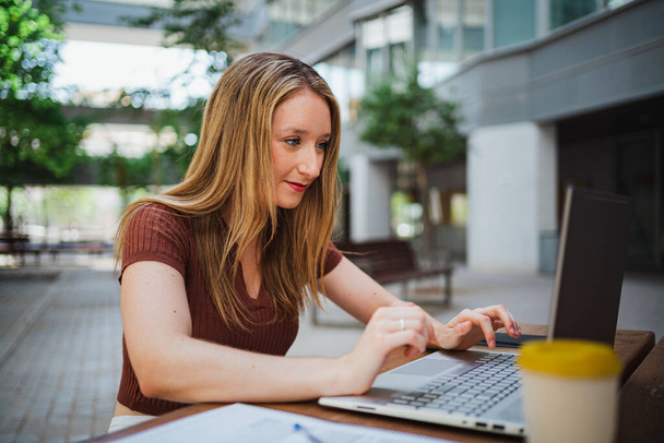 Studentin arbeitet mit ihrem Laptop auf dem Campus der Universität - Foto, Bild