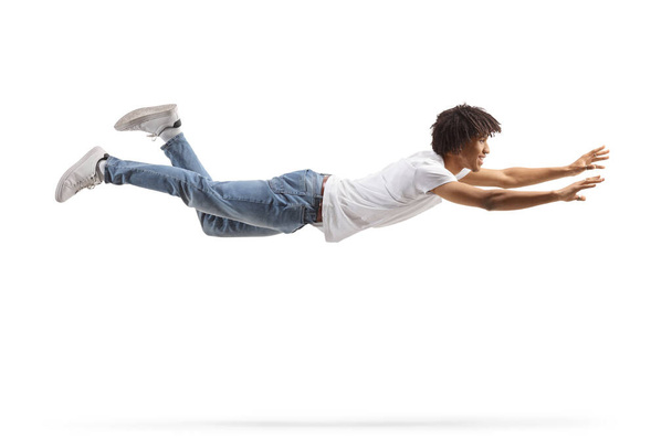 African american guy in jeans and white t-shirt flying and trying to catch something isolated on white background - Fotoğraf, Görsel
