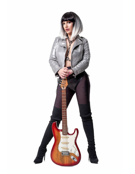 Beautiful woman in sexy funky outfit and boots holding electric guitar on white background - Фото, зображення