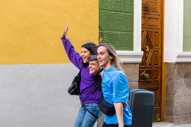 Giovani amici diversi che si abbracciano mentre camminano per strada con orgoglio bandiera arcobaleno. Concetto di Lgbtq. - Foto, immagini