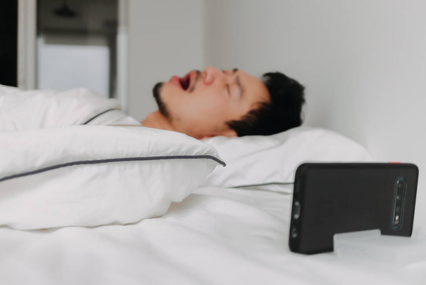 Asian man just wake up and yawn after an overnight video call with his girlfriend. - Fotografie, Obrázek