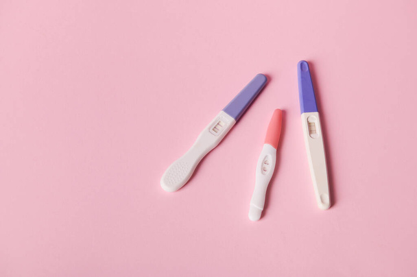 Top view of inkjet pregnancy test kits with a biochemical reaction between hCG and urine appearing in two bars, isolated pink color background. Ovulation day. Planning maternity. Gynecological concept - 写真・画像