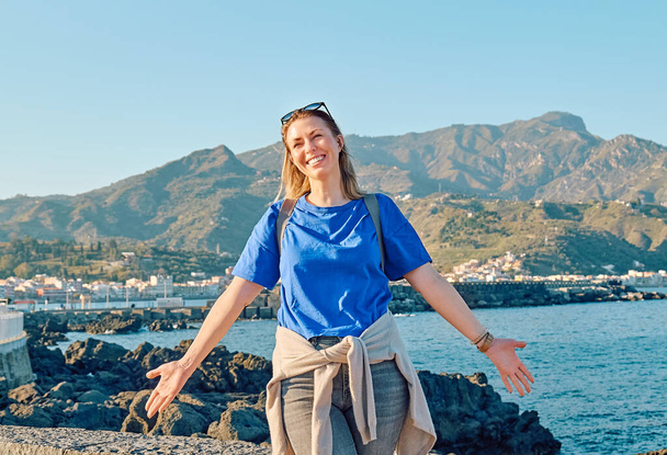 Happy woman tourist spreading arms enjoying freedom in seaside. Female traveler relaxing in serene nature. Mental health, wellness, adventure travel and healthy lifestyle. - Φωτογραφία, εικόνα