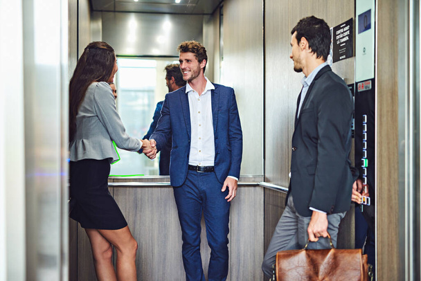 Great partnerships can begin anywhere. businesspeople meeting and greeting in an elevator - 写真・画像