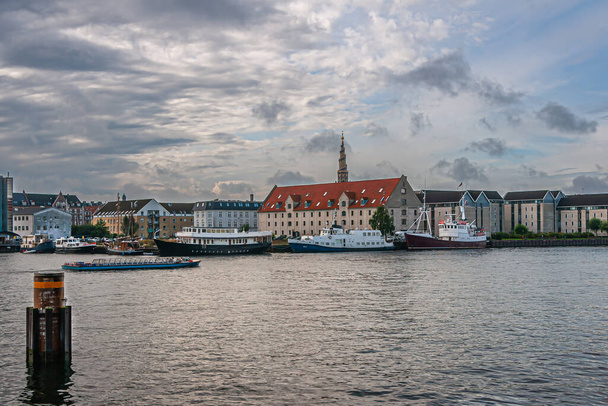 Copenhague, Dinamarca - 12 de setembro de 2010: Vista sul de Havnepromenade em Nyhavn mostra armazéns históricos, agora residenciais e barcos. Atrás, Igreja de Nosso Salvador torre - Foto, Imagem