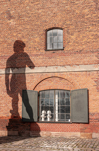 Copenhagen, Denmark - September 13, 2010: Michelangelo David green bronze statue on pedestal shadow against red brick historic warehouse facade - Foto, Imagen