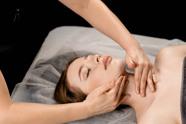 Neck and face massage in the spa. Masseur is making facial beauty treatments for attractive female model. Relaxation - Valokuva, kuva
