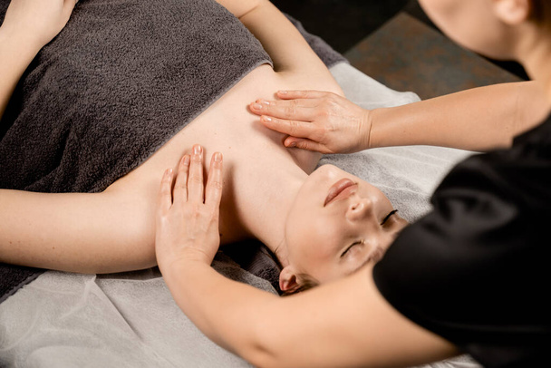 Массер займається лікуванням краси облич для привабливої жіночої моделі. Шия і масаж обличчя в спа. Релаксація - Фото, зображення
