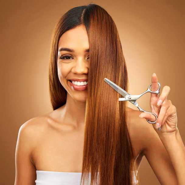 Hair care, beauty and portrait of woman with scissors and smile for luxury salon treatment on brown background. Happy model, brunette hairstyle and cut for split ends, haircut for style in studio - Zdjęcie, obraz