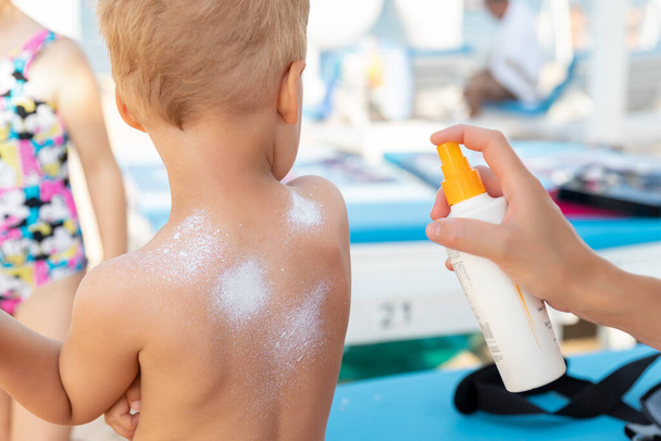 Mother applying sunscreen protection creme on cute little baby boy kid back. Mum using sunblocking lotion to protect baby from sun during summer sea vacation. Child healthcare travel vacation time. - Foto, Imagem