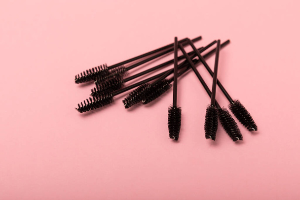 Eyelash extension brushes on a pink background. Brush for combing extended and false eyelashes. Brush for straightening eyelashes and eyebrows. - Foto, Imagem