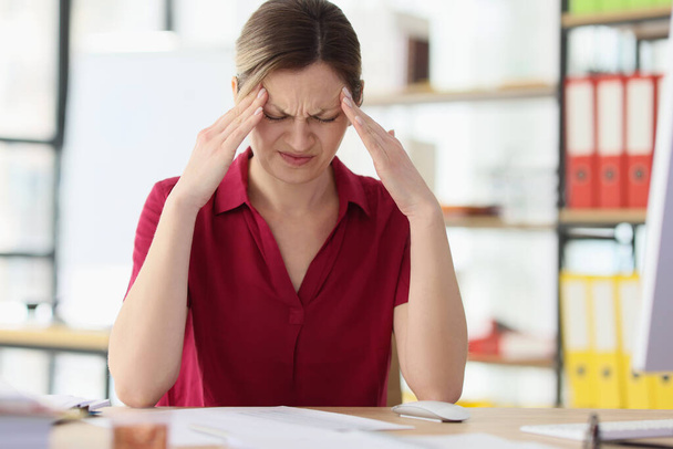 İş yerinde sıkı migreni olan kadın ofis çalışanı. Çalışan işyerinde gerilim yüzünden stresli. Aşırı çalışmanın yol açtığı baş ağrısı sorunları - Fotoğraf, Görsel