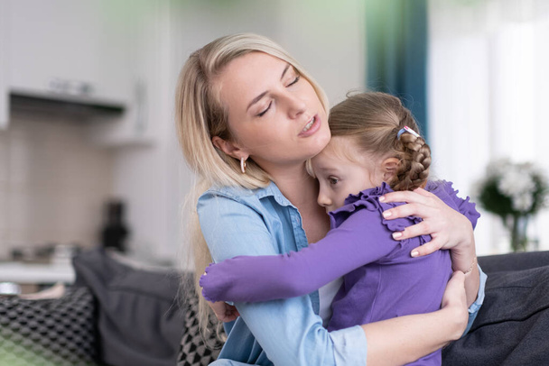 Caring mother comforting and hugging upset scared little girl at home sitting on sofa, Parent protection and support concept. - Φωτογραφία, εικόνα