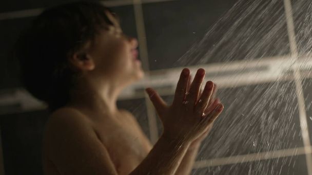Washing happy child with shower head in slow motion. One small boy clapping hands during night bathing routine at night - Photo, image