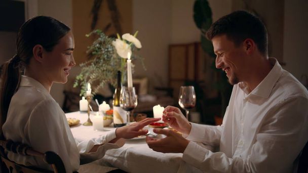 Happy guy wearing engagement ring at evening room. Loving woman saying yes at romantic dinner atmosphere. Enamoured couple touching foreheads bonding at night place. Celebrating marriage proposal - Foto, imagen