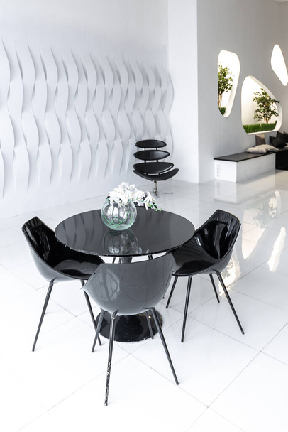 Luxurious futuristic trendy modern interior in contrasting black and white colors with interesting fashionable black furniture and decorated wall - Foto, Imagen