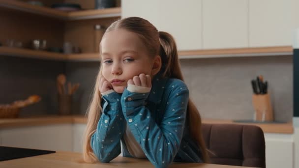 Moving camera portrait sad little offended Caucasian child girl kid at kitchen say no answer not never shaking head negative disagree family misunderstanding upset daughter unhappy displeased at home - Footage, Video