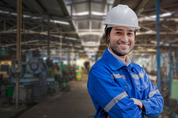 Portrait of manual man worker is standing with confident with blue working suite dress and safety helmet in front machine and equipment for heavy industry factory. Steel plant for production. - Photo, Image