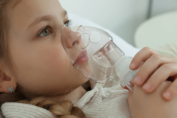 Little girl using nebulizer for inhalation indoors, closeup - Foto, imagen