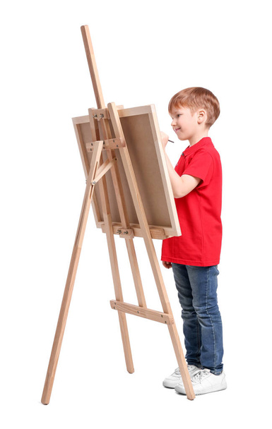 Little boy painting against white background. Using easel to hold canvas - Foto, afbeelding