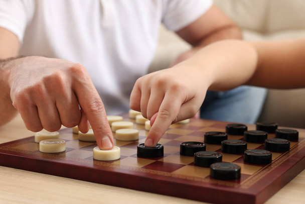 Father playing checkers with his son at table in room, closeup - Fotoğraf, Görsel