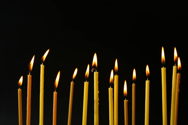 Many burning church candles on black background - Фото, зображення