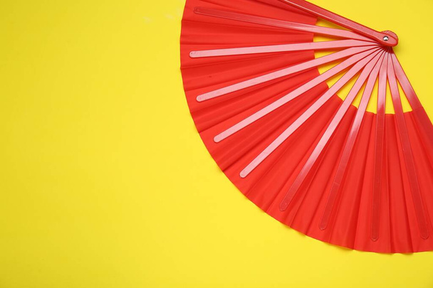 Bright red hand fan on yellow background, top view. Space for text - Foto, Imagen