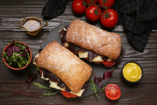 Delicious sandwiches with tasty filling and ingredients on wooden table, flat lay - Photo, image