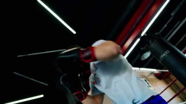 Boxeo gimnasio un boxeador entrena sus golpes golpeando saco de boxeo - Imágenes, Vídeo
