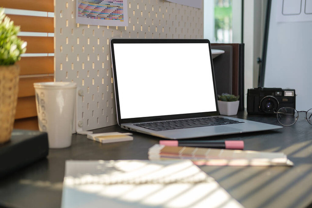 Креативное дизайнерское рабочее место с ноутбуком, цветными образцами и камерой на деревянном столе. - Фото, изображение