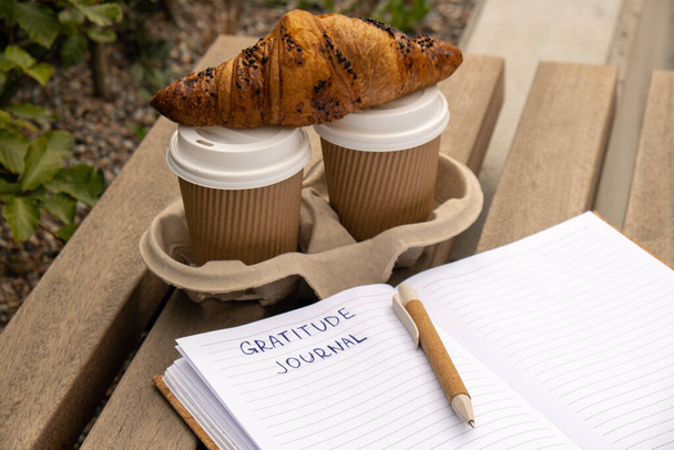 Escribiendo Gratitude Journal en un banco de madera. Café y croissants rutina de la mañana. Hoy estoy agradecido. Diario del descubrimiento del uno mismo, autorreflexión escritura creativa, desarrollo personal del uno mismo del crecimiento - Foto, Imagen