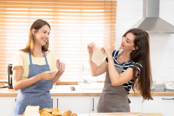 Two caucasian women cooking pizza together in the kitchen. The concept of home cooked food and LGBT relationships. family and diversity concept. lgbt love. - 写真・画像