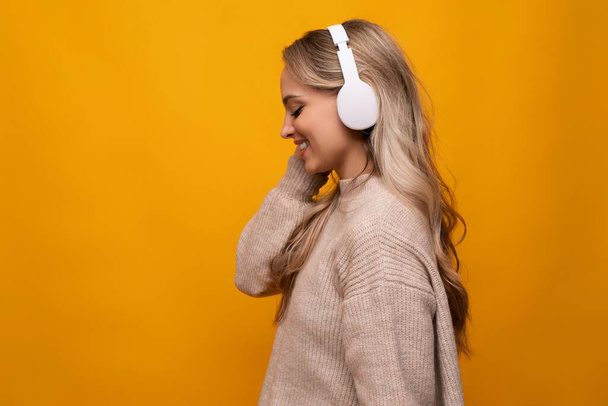 mignonne dame écoute joyeusement de la musique avec de gros écouteurs sur fond orange. - Photo, image