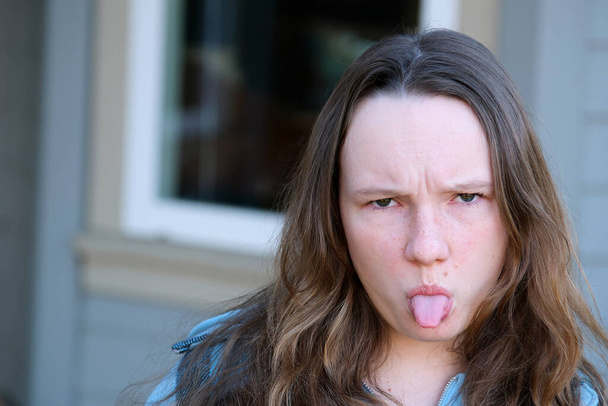 junges Mädchen wütender Teenager streckte ihre Zunge blickt in Rahmen Nahaufnahme Gesicht ist unzufrieden wütend, so dass ich nicht sagte, keine Adoleszenz psychische Probleme der Kommunikation mit Kindern in diesem Alter - Foto, Bild