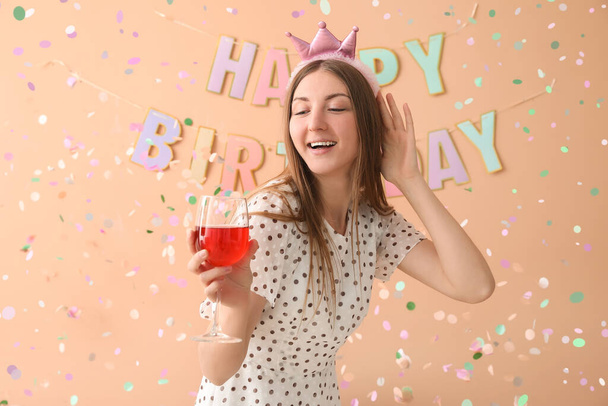 Bir bardak şarapla mutlu genç bir kadın bej arka planda doğum gününü kutluyor. - Fotoğraf, Görsel