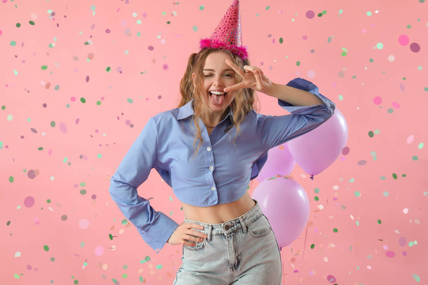 Šťastná mladá žena slaví narozeniny na růžovém pozadí - Fotografie, Obrázek