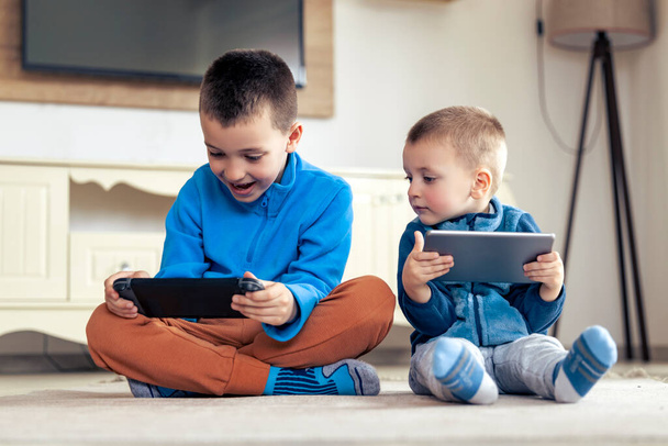 Αγόρια που παίζουν βιντεοπαιχνίδια στο tablet στο σπίτι. - Φωτογραφία, εικόνα