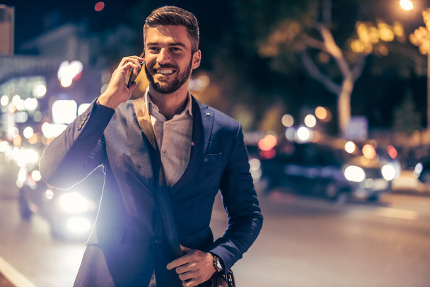 Geceleri şehirde akıllı telefon kullanan yakışıklı bir adam.. - Fotoğraf, Görsel