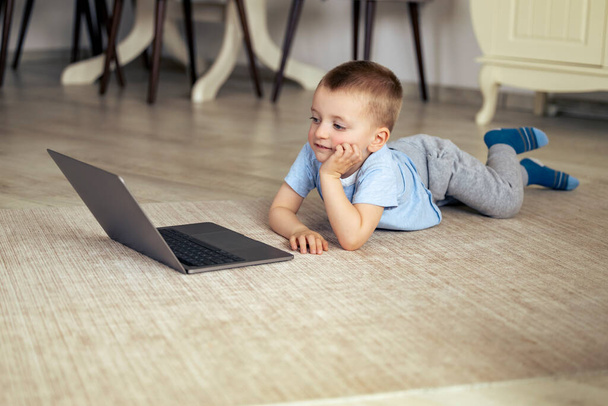 Mały chłopiec z laptopem oglądający kreskówki w domu. - Zdjęcie, obraz