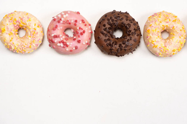 Four donuts in a row - white, pink and chocolate on a white background top view. - Foto, immagini