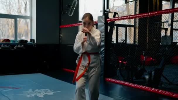 meisje praktijken karate in sportschool vrouw in kimono praktijken bewegingen en stelt vechtsport - Video