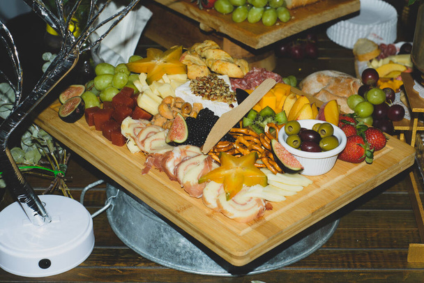 Cheese platter with fruits and cold meats during an evening celebration - Foto, imagen