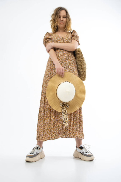Large summer hat in the hands of a woman dressed in a brown dress isolated on a white background. - Fotoğraf, Görsel