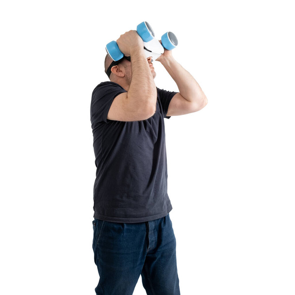 Unsportsmanlike middle-aged man wearing virtual reality glasses with dumbbells. Isolated on a white background. - Photo, image
